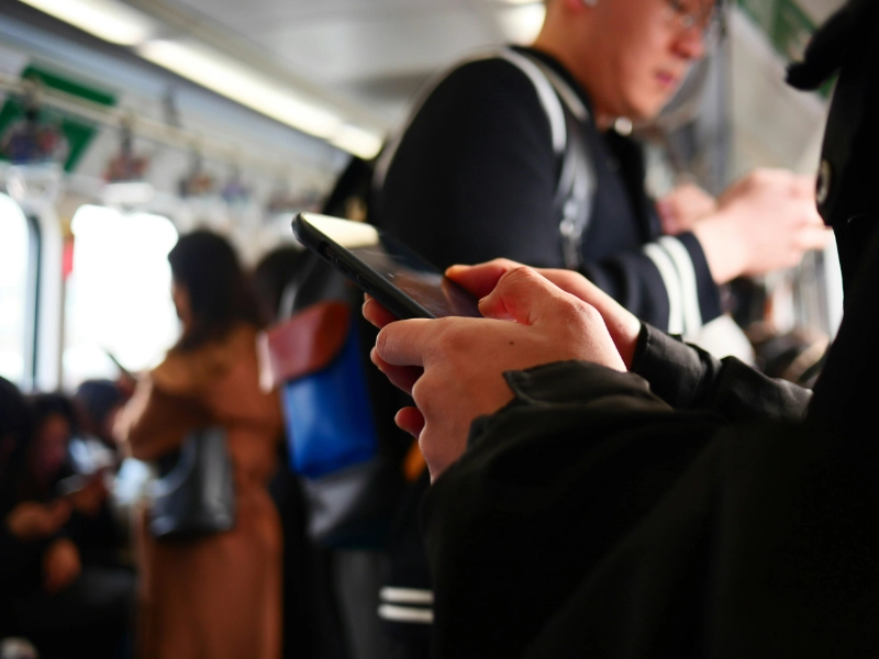 Someone's hands using a phone on the subway. Credit: Chang Hank, via Unsplash.