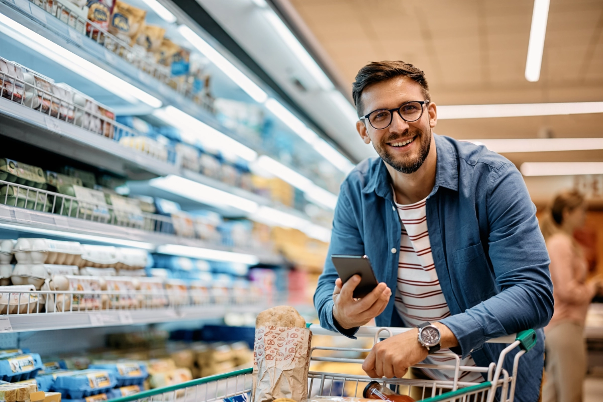 Photograph of a man using a mobile phone in a grocery store. Credit: Drazen Zigic, via iStock.
