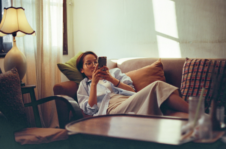 A woman laying on a couch using her phone. Credit: Nguyễn Hiệp, via Unsplash.