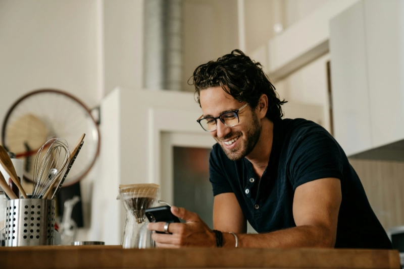 Man in black crew neck t-shirt wearing black framed eyeglasses checking his phone. Credit: Oveth Martinez, via Unsplash.